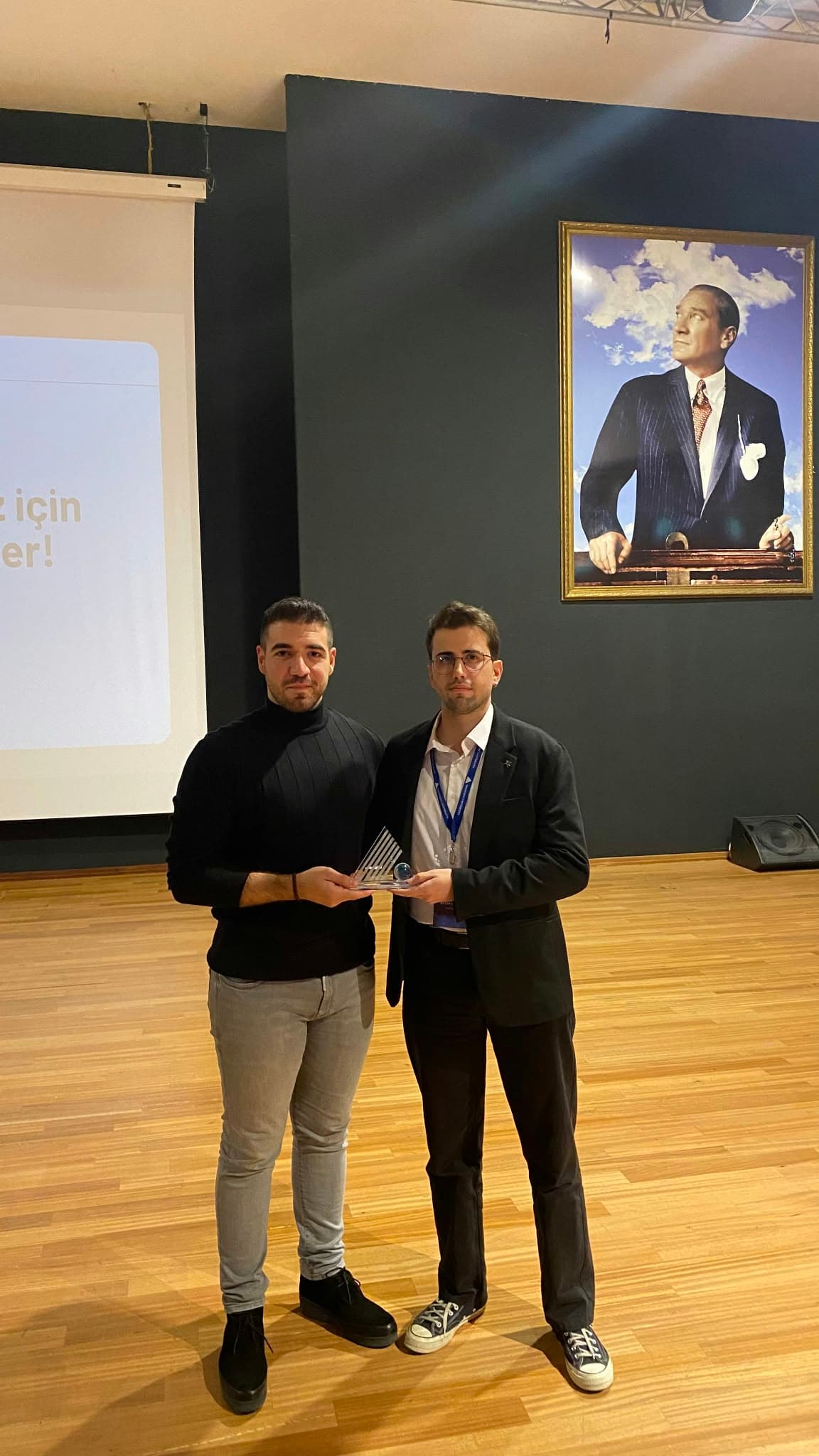 Emrah Kalfa receiving an award on stage at a university event.